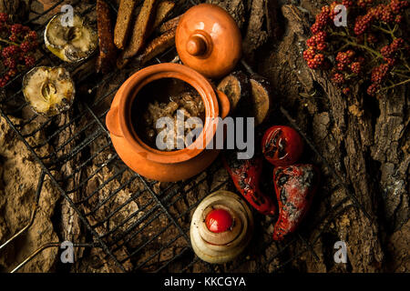 Piatto vegetariano in una pentola di creta con arrosti di verdure alla griglia su uno sfondo di corteccia di albero Foto Stock