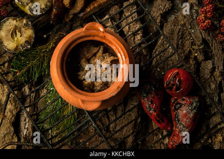 Piatto vegetariano in una pentola di creta con arrosti di verdure alla griglia su uno sfondo di corteccia di albero Foto Stock