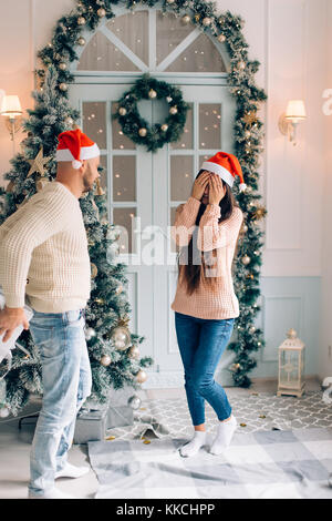 Tagliate il colpo di un uomo sorprendente la sua fidanzata con un regalo di Natale. Foto Stock