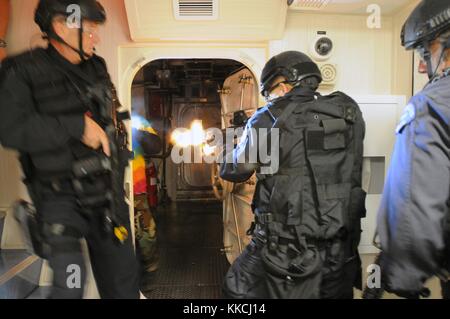 I membri del team di Los Angeles Special Weapons and Tactics SWAT violano una stanza e affrontano obiettivi ostili in un esercizio di addestramento incentrato sulla violazione e sulle tattiche chiare a bordo di navi marittime, San Diego, 2012. Per gentile concessione di Mass Communication Specialist 3rd Class Kristopher Kirsop/US Navy. Foto Stock