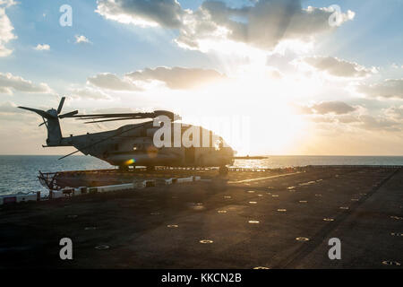 GOLFO ARABICO (Nov. 25, 2017) UN elicottero CH-53E Super Stallion assegnato a Marine Medium Tiltrotor Squadron (VMM) 161 (rinforzato) a bordo della nave d'assalto anfibia USS America (LHA 6) è fissato al ponte di volo in seguito alle operazioni di volo. L'America è il fiore all'occhiello dell'America Amphibious Ready Group e, con il 15° MEU imbarcato, Viene dispiegata nella 5esima area di attività della flotta degli Stati Uniti a sostegno di operazioni di sicurezza marittima progettate per rassicurare alleati e partner e preservare la libertà di navigazione e il libero flusso di commercio nella regione. (STATI UNITI Navy foto b Foto Stock