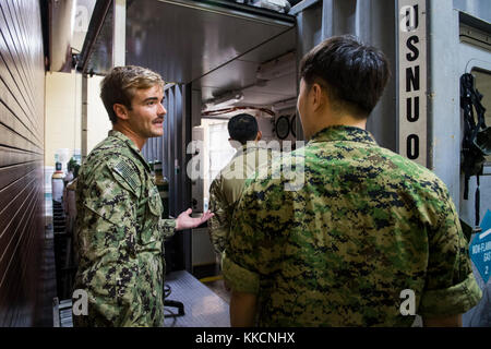 Zach Patrick, assegnato alla Explosive Ordnance Disposal Mobile Unit (EODMU) 5, offre un tour della camera di ricompressione con un servizio di volo speciale della guerra navale della Repubblica di Corea (ROK) durante l'esercizio di ROK MIL alla base navale di Guam, 27 novembre 2017. EODMU-5 conduce operazioni di contromisura e improvvisazione di dispositivi esplosivi, rende sicuri i rischi esplosivi e disarma esplosivi sottomarini come le miniere. (STATI UNITI Fotocamera da combattimento della Marina di Mass Communication Specialist prima Classe Arthurgwain L. Marquez) Foto Stock