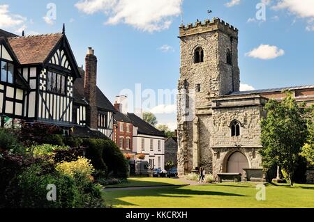 Trinità Santa Chiesa Parrocchiale nel villaggio di Much Wenlock, Shropshire, Inghilterra. 16 C a struttura mista in legno e muratura Guildhall sulla sinistra Foto Stock