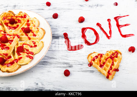 Belga a forma di cuore waffle su sfondo bianco. parola amore fatto da marmellata Foto Stock