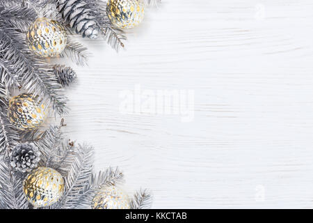 Argento natale rami di albero decorato con luce incandescente ghirlande e pigne di colore bianco su sfondo di legno Foto Stock