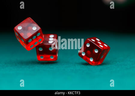 Immagine di vari dadi rossi cadere sul tavolo verde su sfondo nero Foto Stock