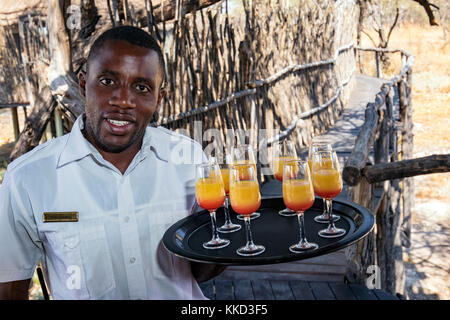 Il personale con drink di benvenuto al onguma tree top camp, onguma Game Reserve, Namibia, Africa Foto Stock