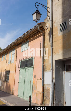Vecchio coral, tan e di colore arancione pallido edifici in stucco con persiane in legno e porte fotografato in corrispondenza di un angolo. una vecchia strada lampada pende sopra. Foto Stock