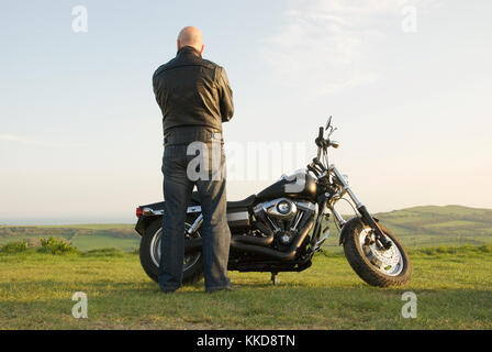 Uomo in piedi accanto a un Harley Davidson Moto in campagna Foto Stock