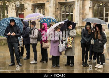 Gli uomini e le donne in piedi nella pioggia, rifugiandosi sotto gli ombrelloni, aspettando pazientemente per la parata di inizio - vicino a York Minster, North Yorkshire, Inghilterra, Regno Unito. Foto Stock