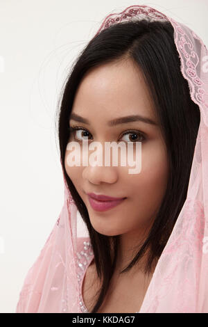 Donna malay indossando rosa baju kurung sullo sfondo bianco Foto Stock