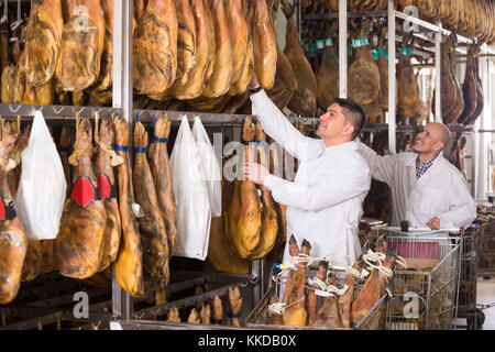 Due qualità maschile ispettori in tute bianche condizione di controllo di jamon snodi a jamon factory Foto Stock