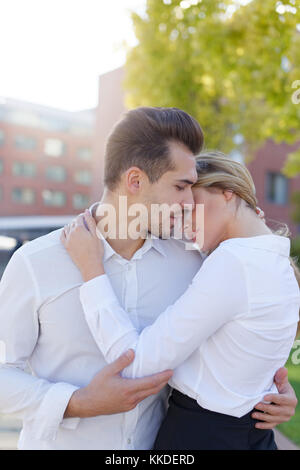 Giovane coppia caucasica abbracciare ogni altra mattina in città, amore Foto Stock