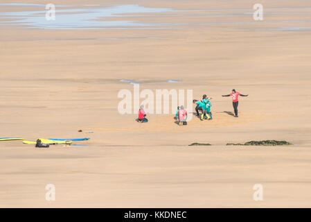 Surf - istruttori di una scuola di surf scuola di surf e studenti giovani in fase di riscaldamento prima di iniziare una lezione di surf a Fistral Beach Newquay Co Foto Stock