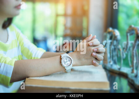 Donna orante della Sacra Bibbia nella mattina. adolescente mano con la Bibbia pregando,mani giunte in preghiera in una Sacra Bibbia nel concetto di chiesa per la fede, Foto Stock