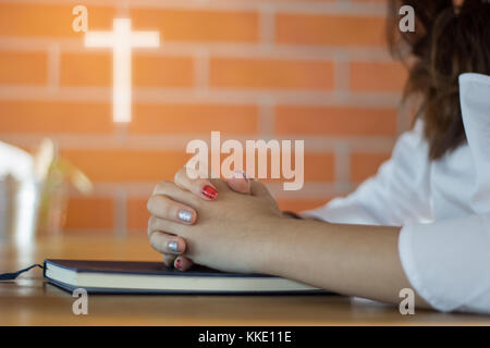 Donna orante della Sacra Bibbia nella mattina. adolescente mano con la Bibbia pregando,mani giunte in preghiera in una Sacra Bibbia nel concetto di chiesa per la fede, spiri Foto Stock
