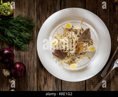 Un piatto di carne e formaggio, decorata con uova di quaglia e cipolla su tavole di legno, vista dall'alto Foto Stock