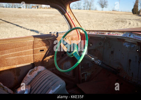 Vecchio martoriata verde volante in un arrugginito spogliato scatafascio auto abbandonate in un campo rurale Foto Stock