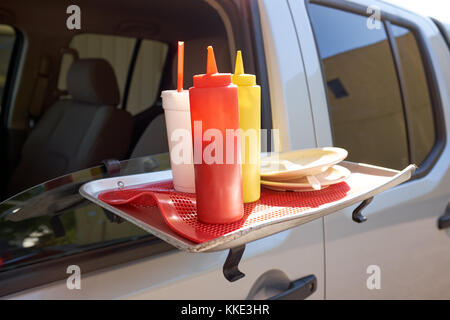 Plastica di ketchup e senape erogatori su un portatile tabella allegata al davanzale di una vettura ad un drive through ristorante Foto Stock