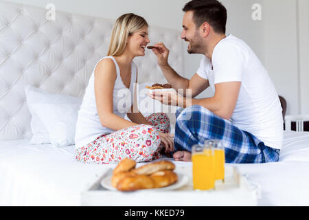 Giovane coppia attraente avente la colazione a letto Foto Stock