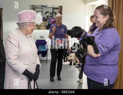 La regina Elisabetta II è introdotta a 12 settimane di Labrador Puppy Flint dal suo allenatore Ruth Narracott mentre lei visita le strutture della Canine Partners Charity a Midhurst in Sussex. Foto Stock