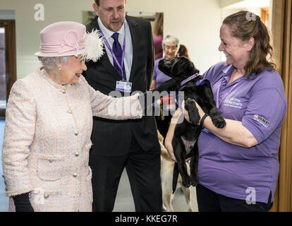 La regina Elisabetta II è introdotto per 12 settimane vecchio cucciolo di Labrador "Flint" con il suo trainer Ruth Narracott come ella tours servizi a "canino Partner" la carità in Midhurst in Sussex. Foto Stock