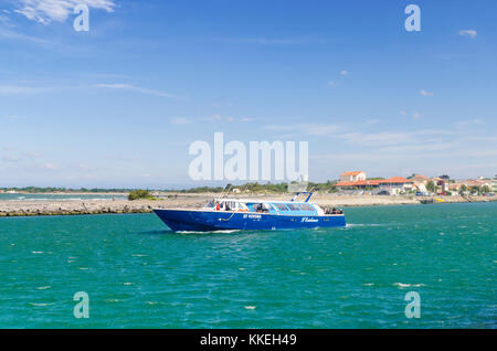 Imbarcazione turistica esce dalla bocca del fiume Herault, in Le Grau d Agde, Herault, Occitanie, Francia Foto Stock