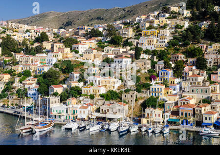 Barche ormeggiate lungo il panoramico lungomare porto di Yialos città sull isola di Symi, Grecia Foto Stock