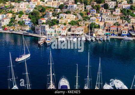 Primo piano sui montanti barche e yacht ormeggiati lungo il panoramico lungomare porto di Yialos città sull isola di Symi, Grecia Foto Stock