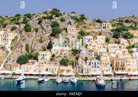 Barche ormeggiate lungo il panoramico lungomare porto di Yialos città sull isola di Symi, Grecia Foto Stock