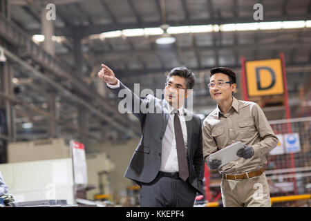 Imprenditore cinese e l'ingegnere parlando in fabbrica Foto Stock