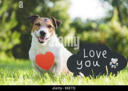 Adorabile cane a forma di cuore pendente e firma manoscritta "ti amo" sulla lavagna Foto Stock