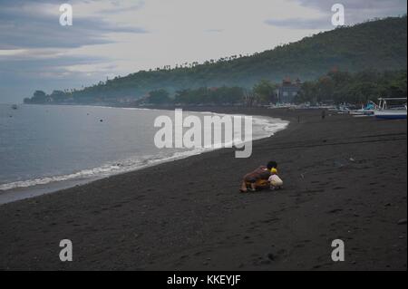 Bali. 2 dicembre 2017. La gente del posto gioca sulla spiaggia di Amed a Karangasem, Bali, Indonesia, 2 dicembre. 2017. Gli impatti derivanti dall'aumento delle attività vulcaniche del Monte Agung nell'isola di Bali in Indonesia hanno colpito direttamente coloro che si guadagnano da vivere grazie al turismo di Amed, un'area costiera di Bali orientale che è ben nota per le sue splendide spiagge, i luoghi per il surf e le immersioni. Crediti: Zulkarnai/Xinhua/Alamy Live News Foto Stock