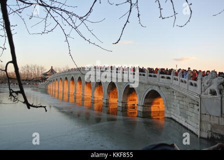 Pechino, Cina. 6 dicembre 2017. I visitatori ammirano il paesaggio del crepuscolo che splende attraverso il ponte del diciassettesimo arco nel Palazzo d'Estate di Pechino, capitale della Cina, il 6 dicembre 2017. Credito: Ma Zhihong/Xinhua/Alamy Live News Foto Stock