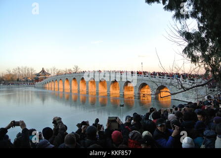 Pechino, Cina. 6 dicembre 2017. I visitatori ammirano il paesaggio del crepuscolo che splende attraverso il ponte del diciassettesimo arco nel Palazzo d'Estate di Pechino, capitale della Cina, il 6 dicembre 2017. Credito: Ma Zhihong/Xinhua/Alamy Live News Foto Stock