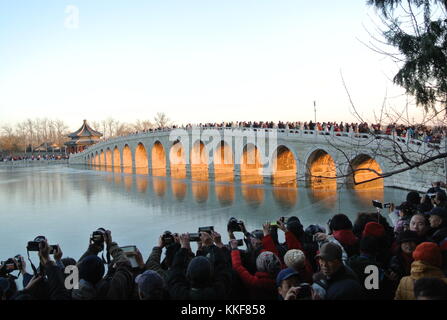 Pechino, Cina. 6 dicembre 2017. I visitatori ammirano il paesaggio del crepuscolo che splende attraverso il ponte del diciassettesimo arco nel Palazzo d'Estate di Pechino, capitale della Cina, il 6 dicembre 2017. Credito: Ma Zhihong/Xinhua/Alamy Live News Foto Stock