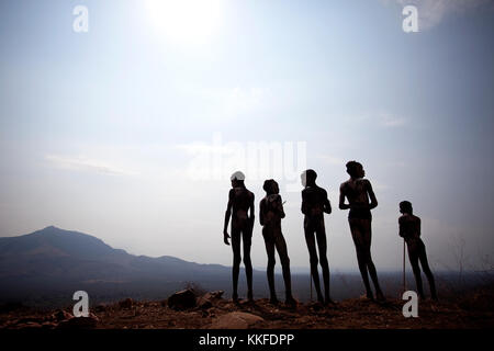 Ssilhouette dei Mursi ragazzi in piedi sopra la valle, valle dell'Omo, Etiopia. Foto Stock