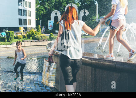 Ivano frankivsk ucraina, 18 giugno 2017. una ragazza è che corrono attorno alla fontana. Un'altra ragazza sta camminando lungo il bordo della holding di sua madre la mano. Foto Stock