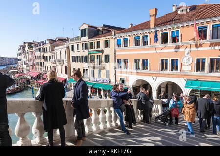 La folla di turisti in piedi sul ponte di Rialto a fotografare il Grand Canal, Venezia, Italia su una soleggiata giornata autunnale Foto Stock