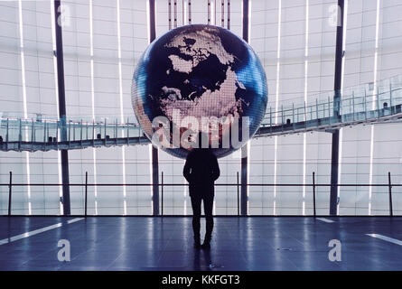 Silhouette di donna guardando un grande pianeta terra, una mostra al miraikan in Odaiba, Giappone, nello stupore Foto Stock