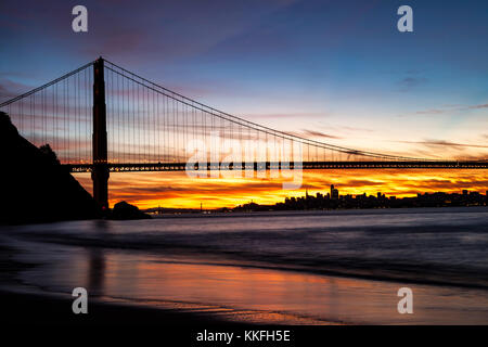 Torre Nord del Golden Gate Bridge in alba ore con il Bay Bridge e San Francisco in background. Foto Stock