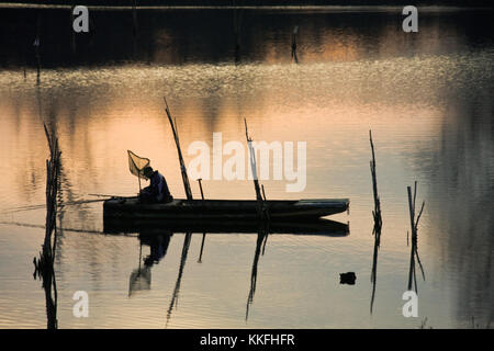 Pescatore in barca sul fiume in sunset Foto Stock