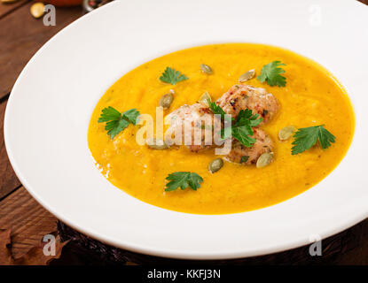 Deliziosa crema di zuppa di zucca con polpette di carne di tacchino carne macinata in una ciotola su una tavola di legno. vista dall'alto. La Giornata del ringraziamento. Foto Stock