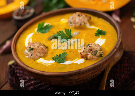 Deliziosa crema di zuppa di zucca con polpette di carne di tacchino carne macinata in una ciotola su una tavola di legno. vista dall'alto. La Giornata del ringraziamento. Foto Stock