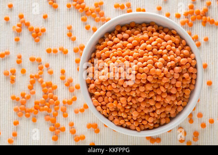 Materie rosso, lenticchie secche nella ciotola bianco sul tavolo Foto Stock