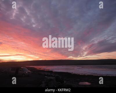 Il sole sorge su Atlantica selvaggia a modo di Doolin Pier, County Clare, Irlanda ruotando il rock pools uno squarcio di colore rosso. Foto Stock