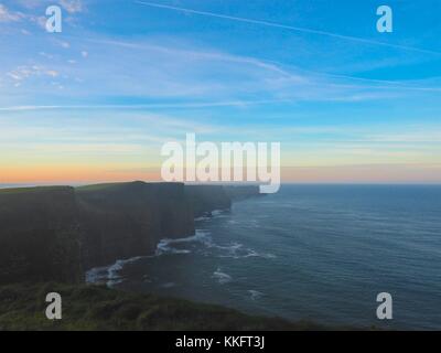 Sunrise sulle scogliere di Moher County Clare Irlanda, Wild Atlantic modo, surf rompe sulle rocce al di sotto. Posizione tranquilla e drammatico. Foto Stock