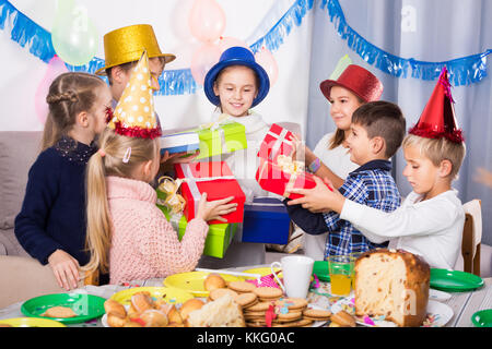 Dei bambini felici presentando doni alla bambina durante la festa di compleanno Foto Stock