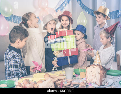 Felici i bambini presentando doni alla bambina durante la festa di compleanno Foto Stock