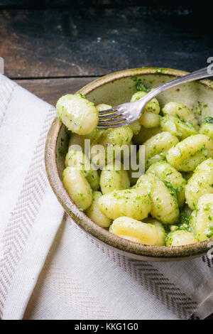 Vaso in ceramica di gnocchi di patate al pesto, servita con forcella vintage sul vecchio tavolo in legno Foto Stock